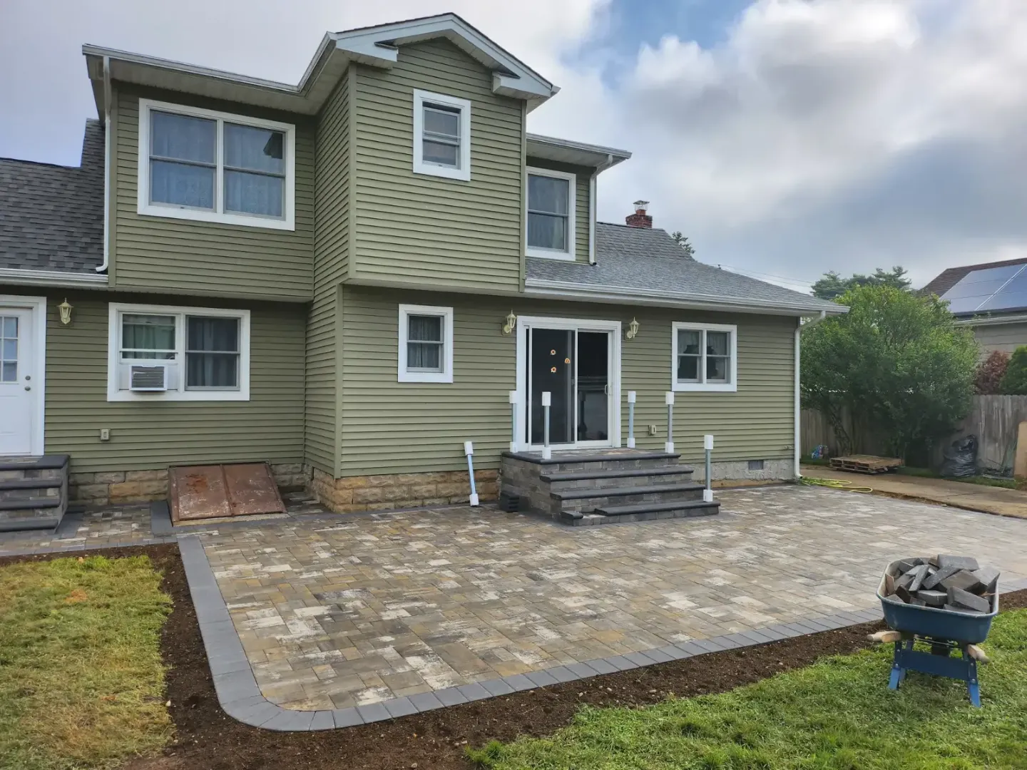 Backyard paver patio with charcoal border and steps by Promaster Maintenance Corp