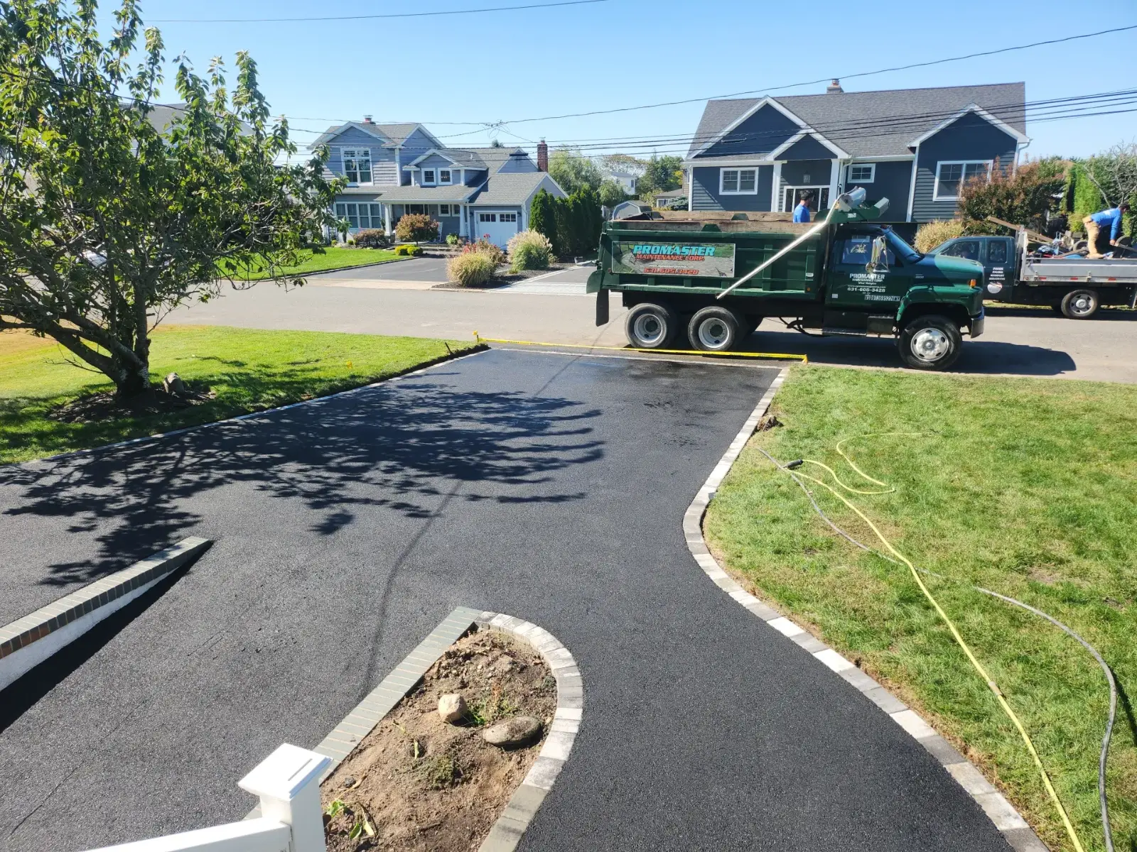 Promaster Maintenance Corp truck and crew finishing a new asphalt driveway on Long Island