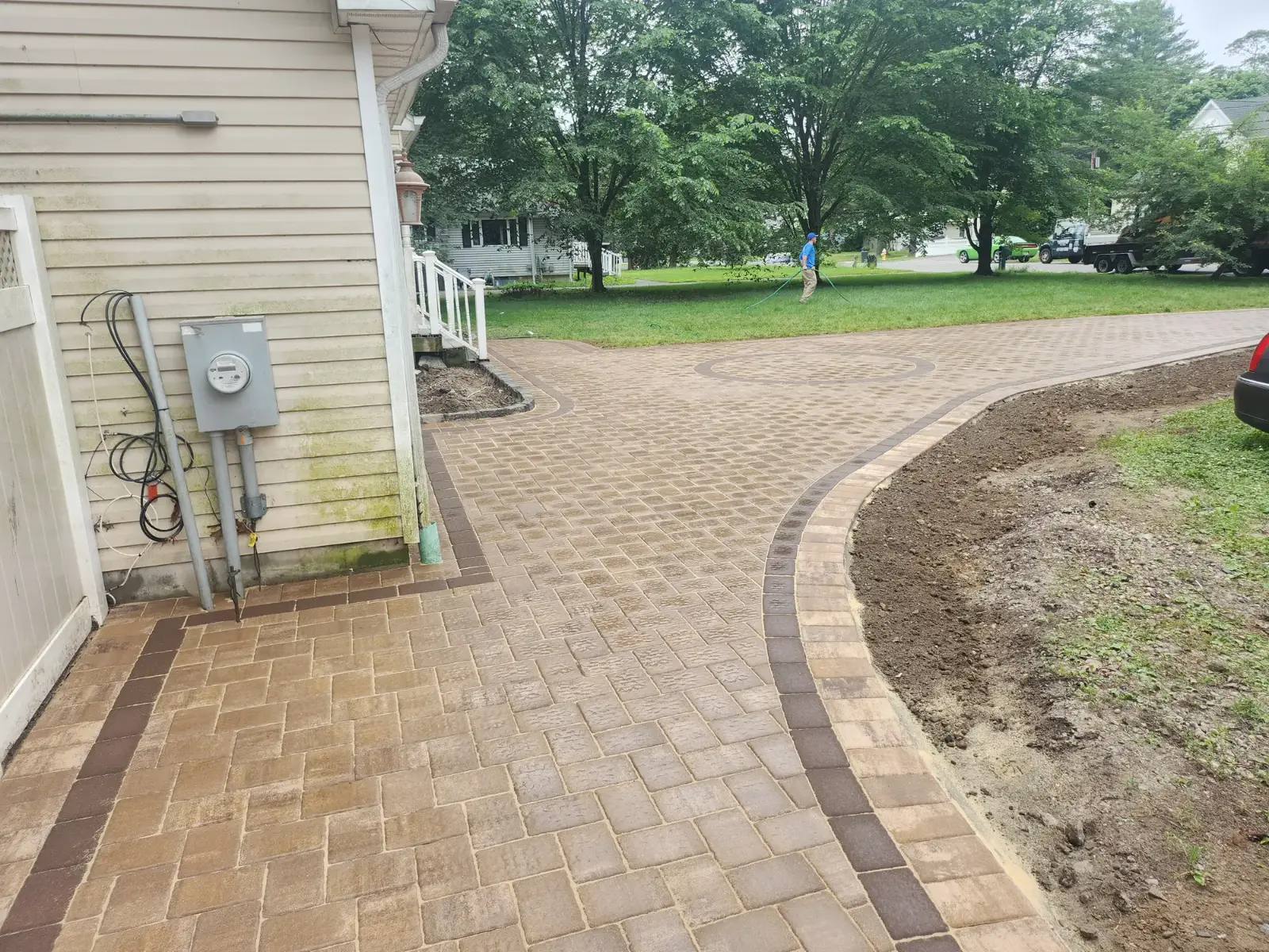 Tan paver driveway with dark soldier-course border and circle inlay by Promaster Maintenance Corp, Long Island