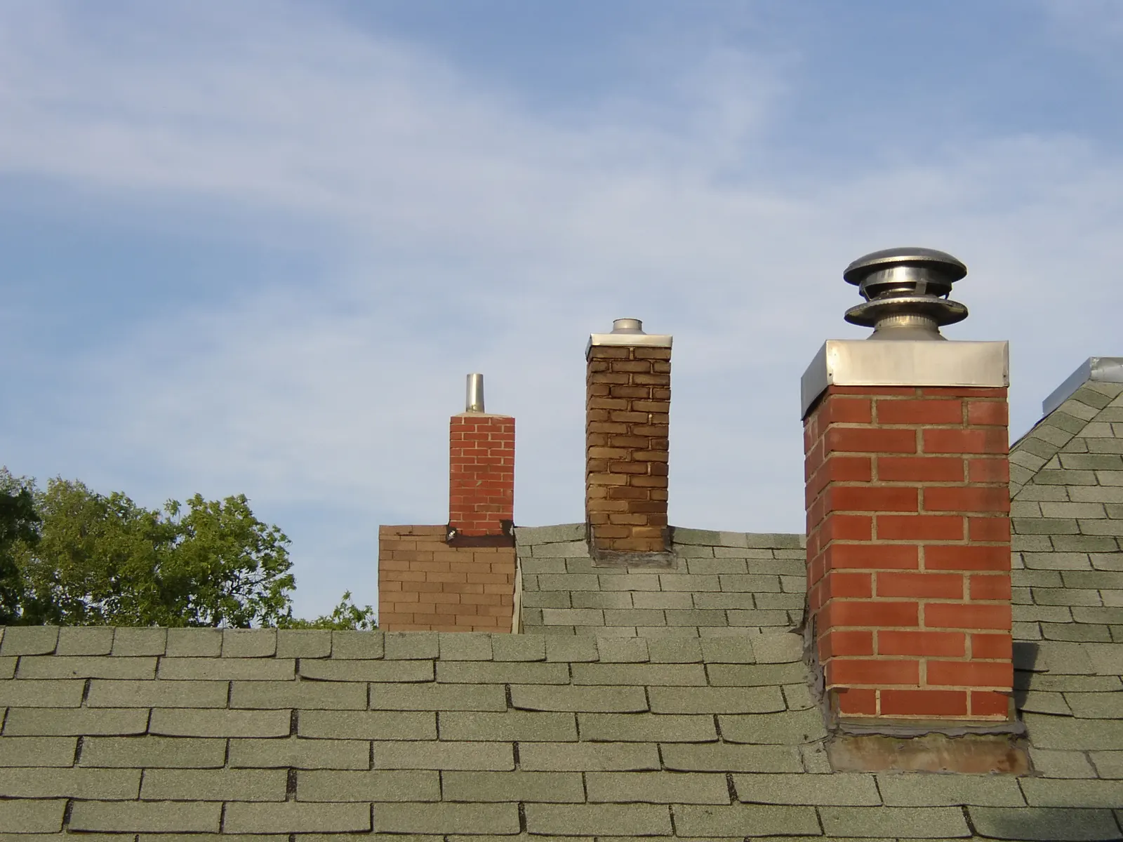 Brick chimneys with caps on a shingle roof